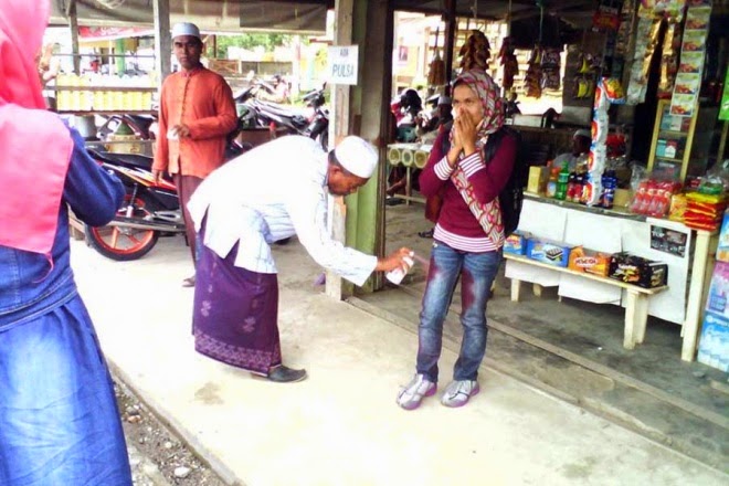 Seorang gadis memakai seluar jeans, dicat seluarnya dengan spray berwarna merah oleh seorang polis moral kerana melanggar kod etika pemakaian yang dibenarkan di Aceh. 