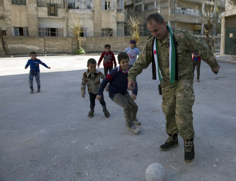 Yasser Nabhan plays football with children in Syria's northern city of Aleppo Saif al-Dawla district on March 11, 2016. Syria's war has transformed 38-year-old Nabhan from a successful textile merchant, to a rebel sniper, to a handicapped administrative assistant.  – AFP pic, March 13, 2016.