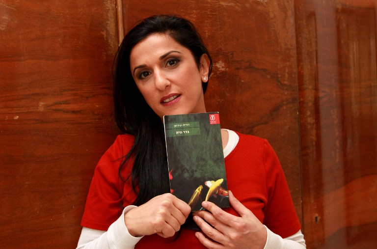 Israeli author Dorit Rabinyan with her Hebrew-language novel titled 'Gader Haya' ('Borderlife') at her house in the coastal city of Tel Aviv. Rabinyan's book has been left off courses in a bid to avoid encouraging relationships between Jews and Arabs. – AFP pic, January 8, 2016.