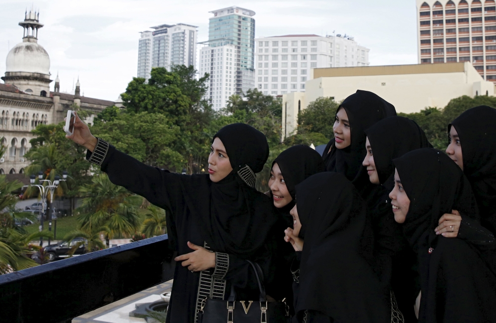 Sekumpulan wanita mengambil gambar 'selfie' di Kuala Lumpur. Lebih ramai wanita Melayu kini gemar memakai jubah daripada baju kurung. – Gambar Reuters, 5 Julai, 2015.